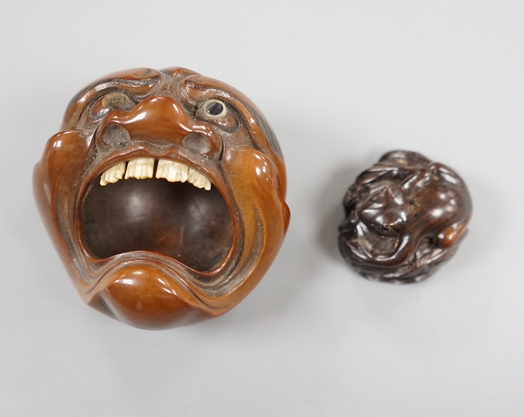 A Japanese mask nut carving wood carving, Meiji period and a netsuke of frogs, marks to bases, largest 7.5cm wide